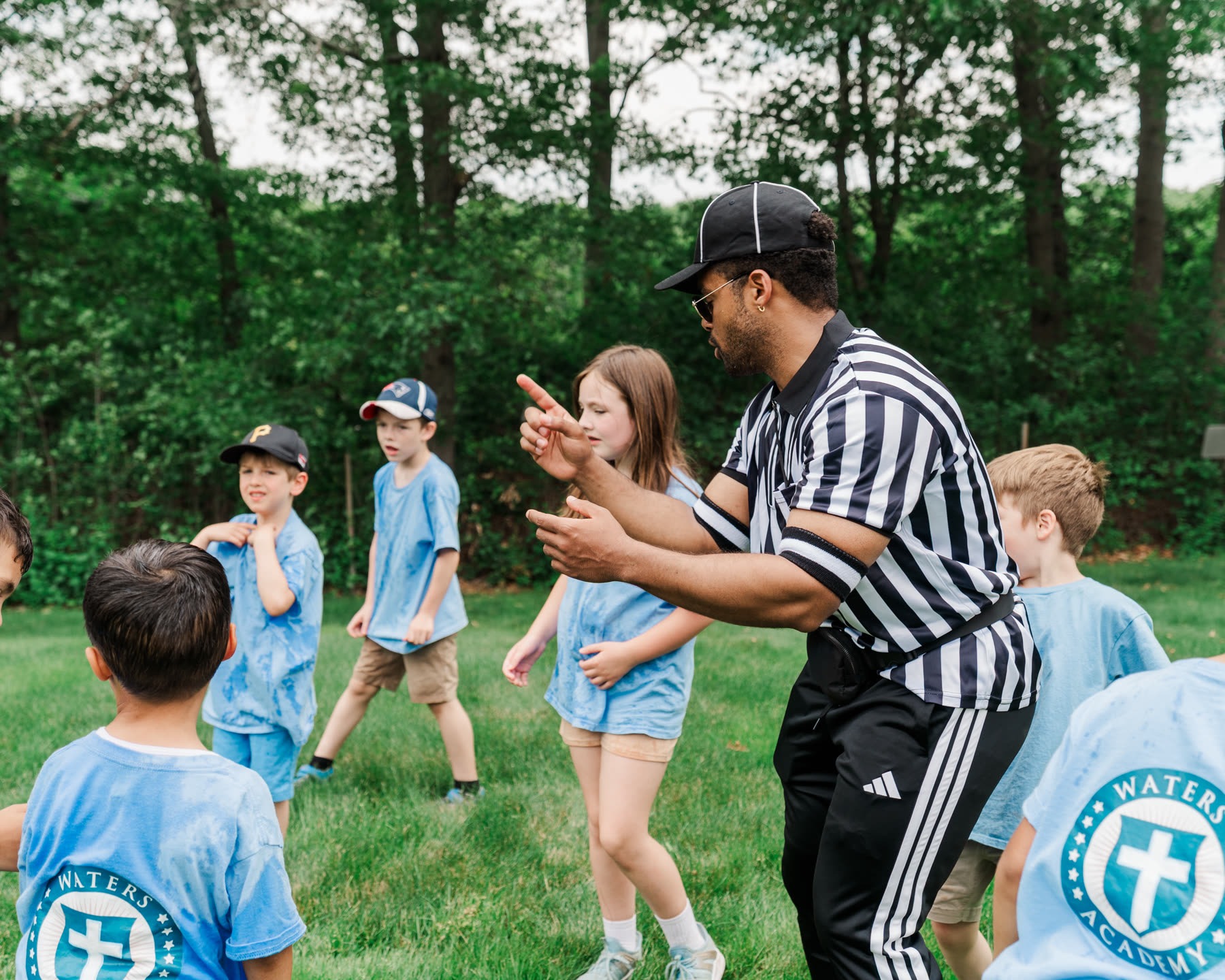 A coach leading Waters Academy students in an outdoor game